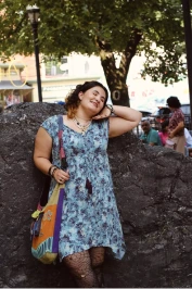Selena posing in front of a large rock.
