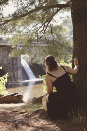 Selena looking at the waterfall from behind a tree.