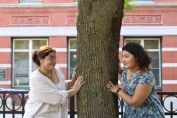 Sofia and Selena looking at each other from opposite sides of a tree.